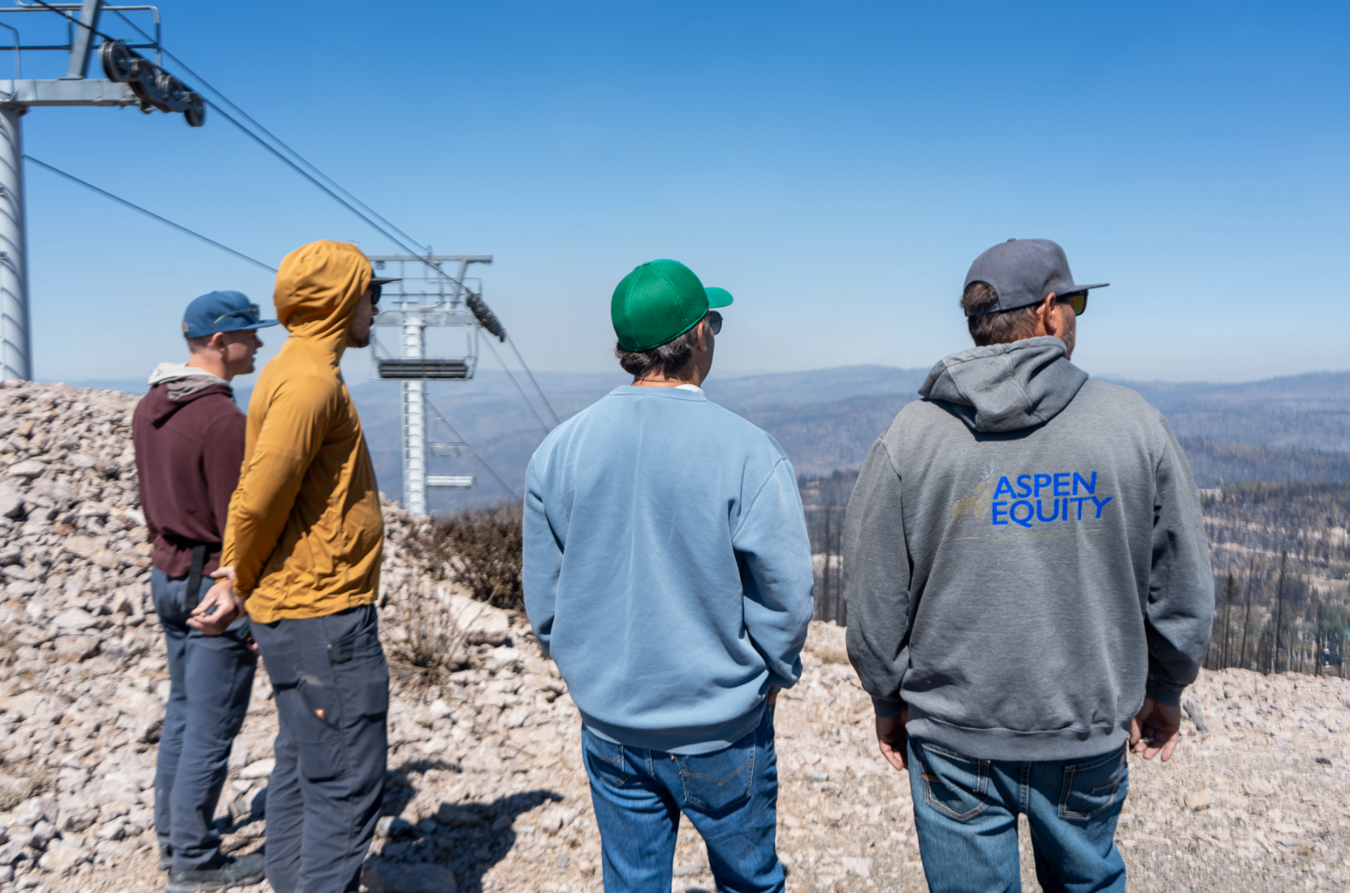 Four people standing at the top of a Tushar Mountain ski lift overlooking the valley